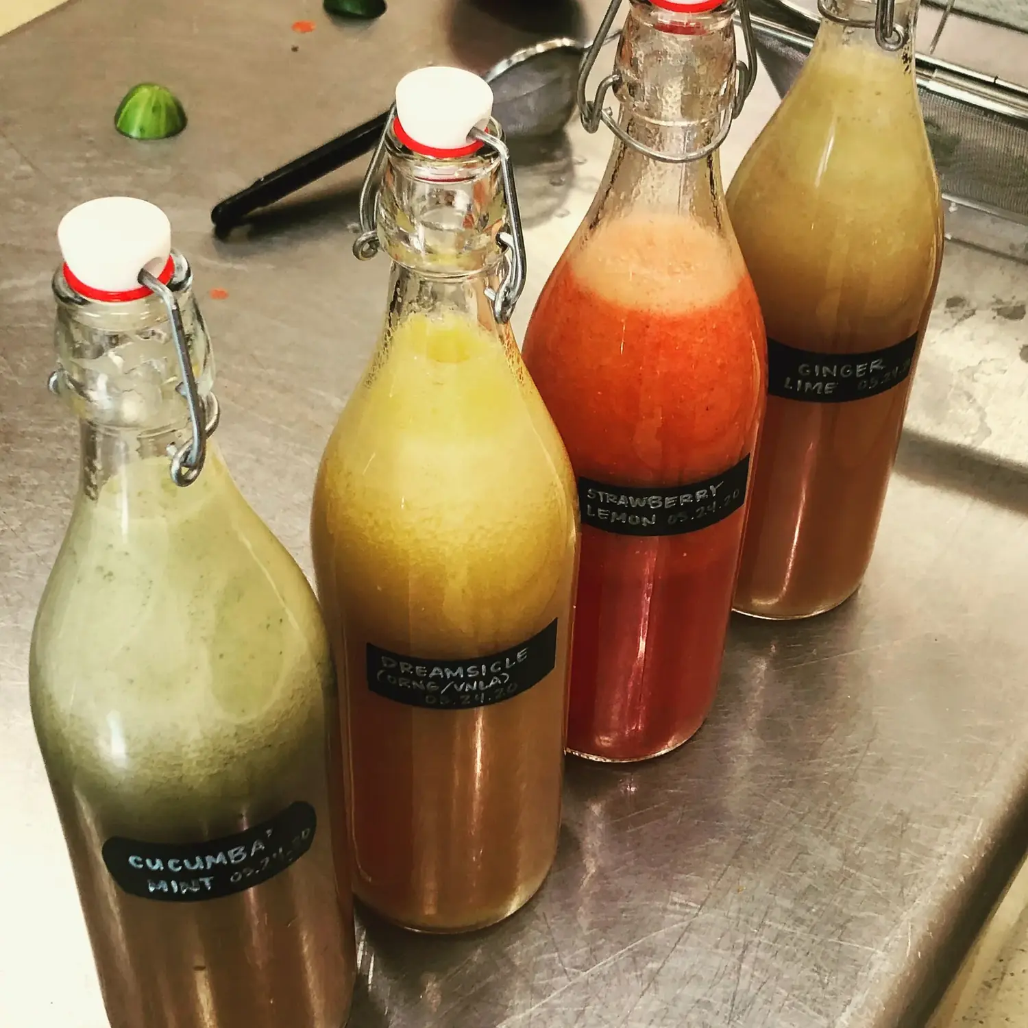 Homemade kombucha in swing-top bottles — cucumber mint, dreamsicle, strawberry lemon, ginger lime