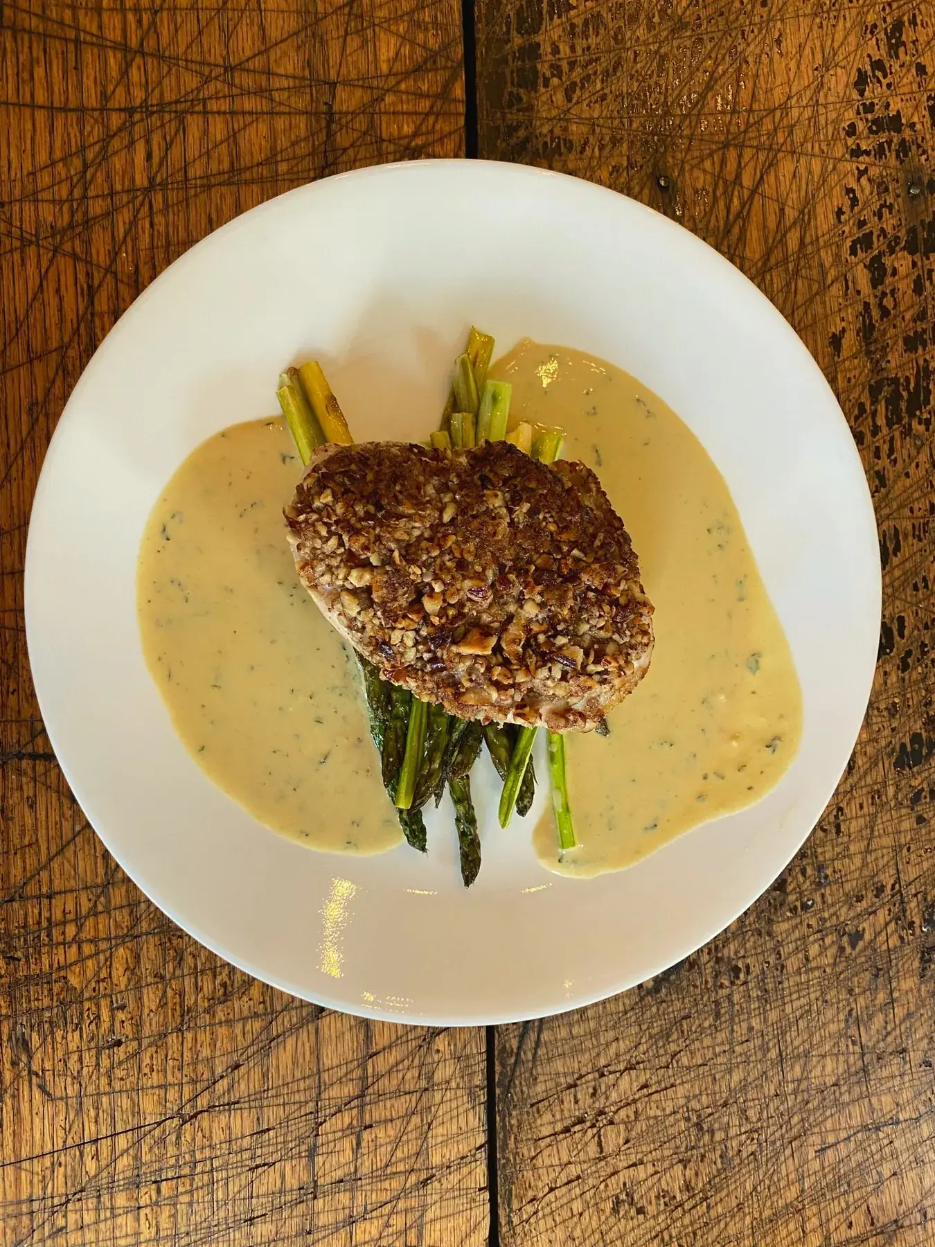 Nut-crusted protein on asparagus with herb cream sauce