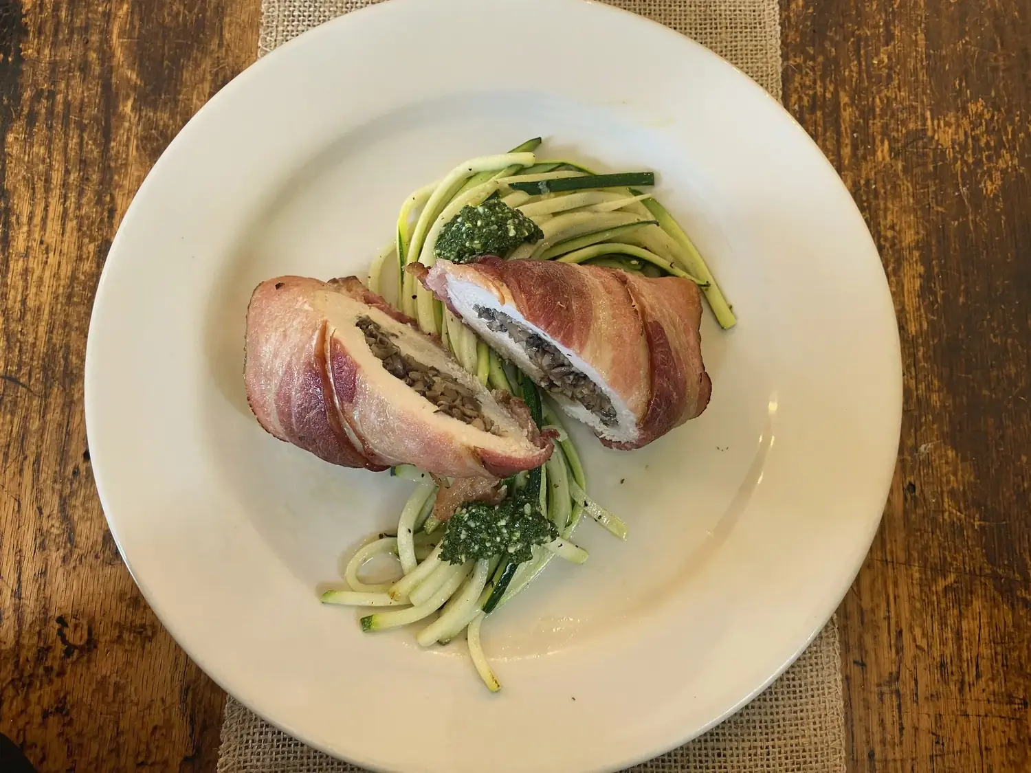 Prosciutto-wrapped stuffed chicken on zucchini noodles with pesto