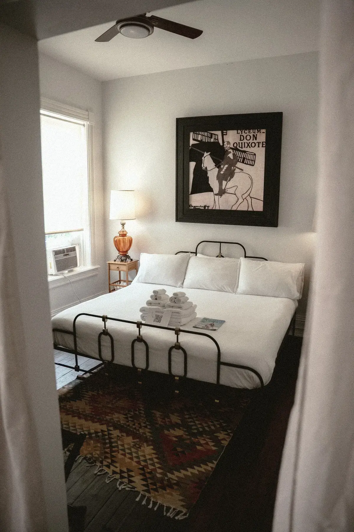 Iron bed with Don Quixote art and curtain framing