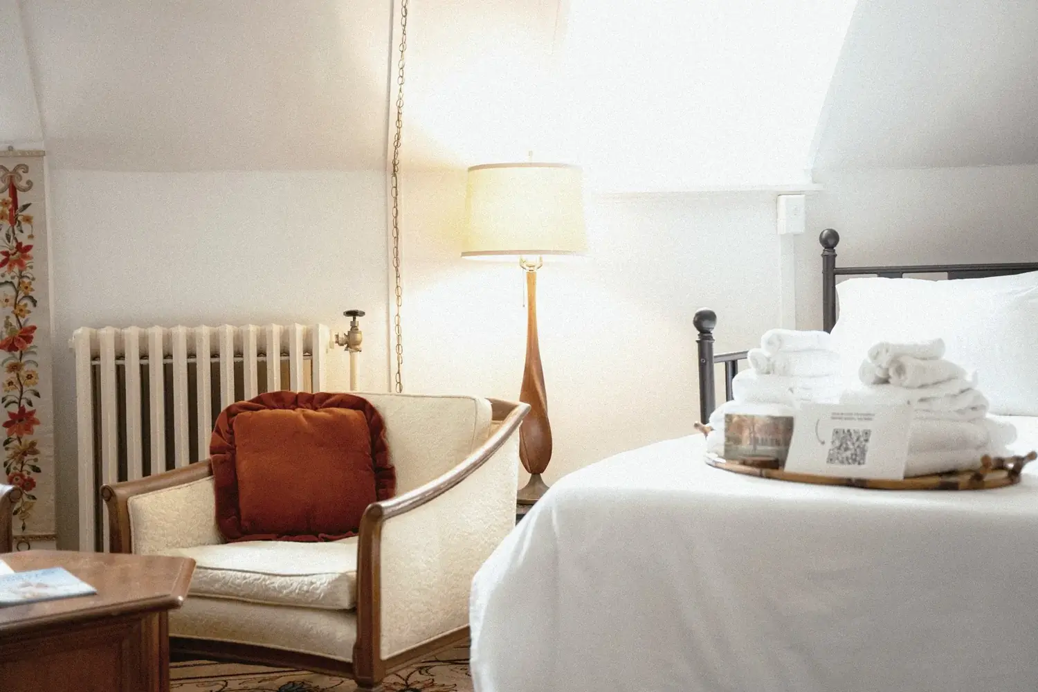 Iron bed with vintage chair, radiator, and warm lamp