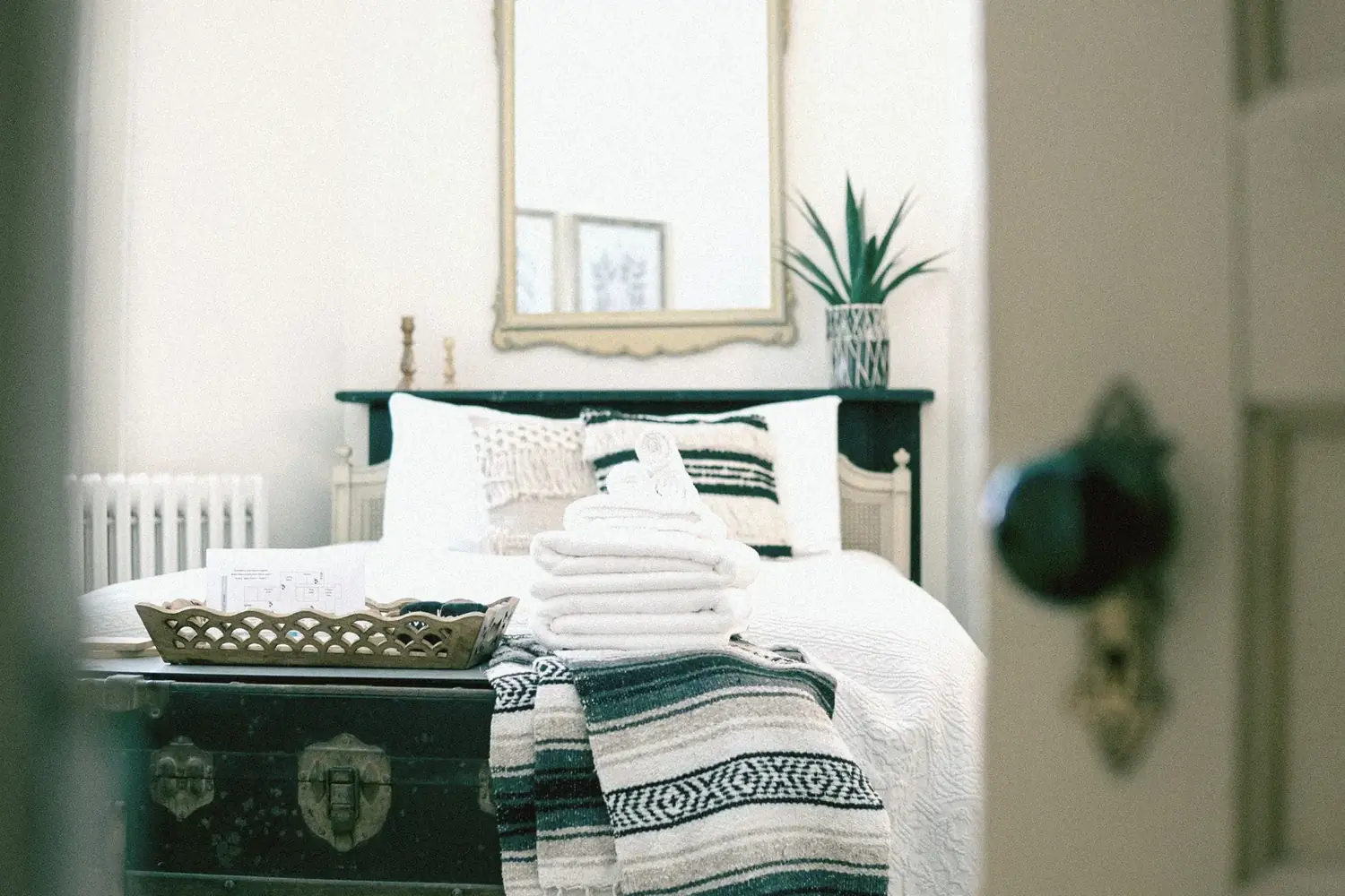 Bedroom through doorway with trunk and folded towels