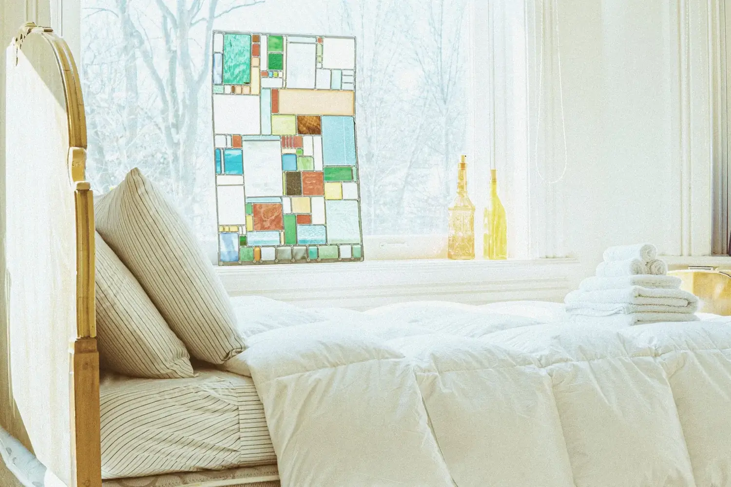 Bright bed beside stained-glass panel window