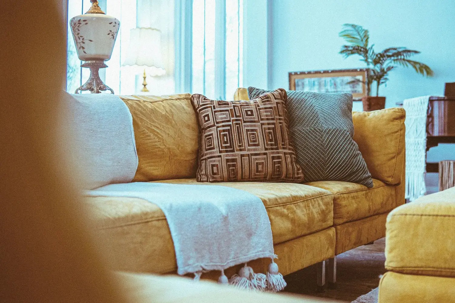 Mustard sofa with layered pillows and bright windows