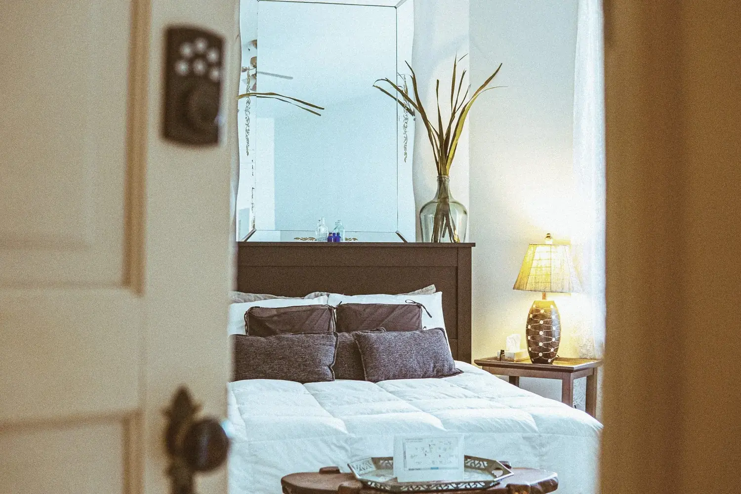 Bedroom framed through doorway with warm lamp glow