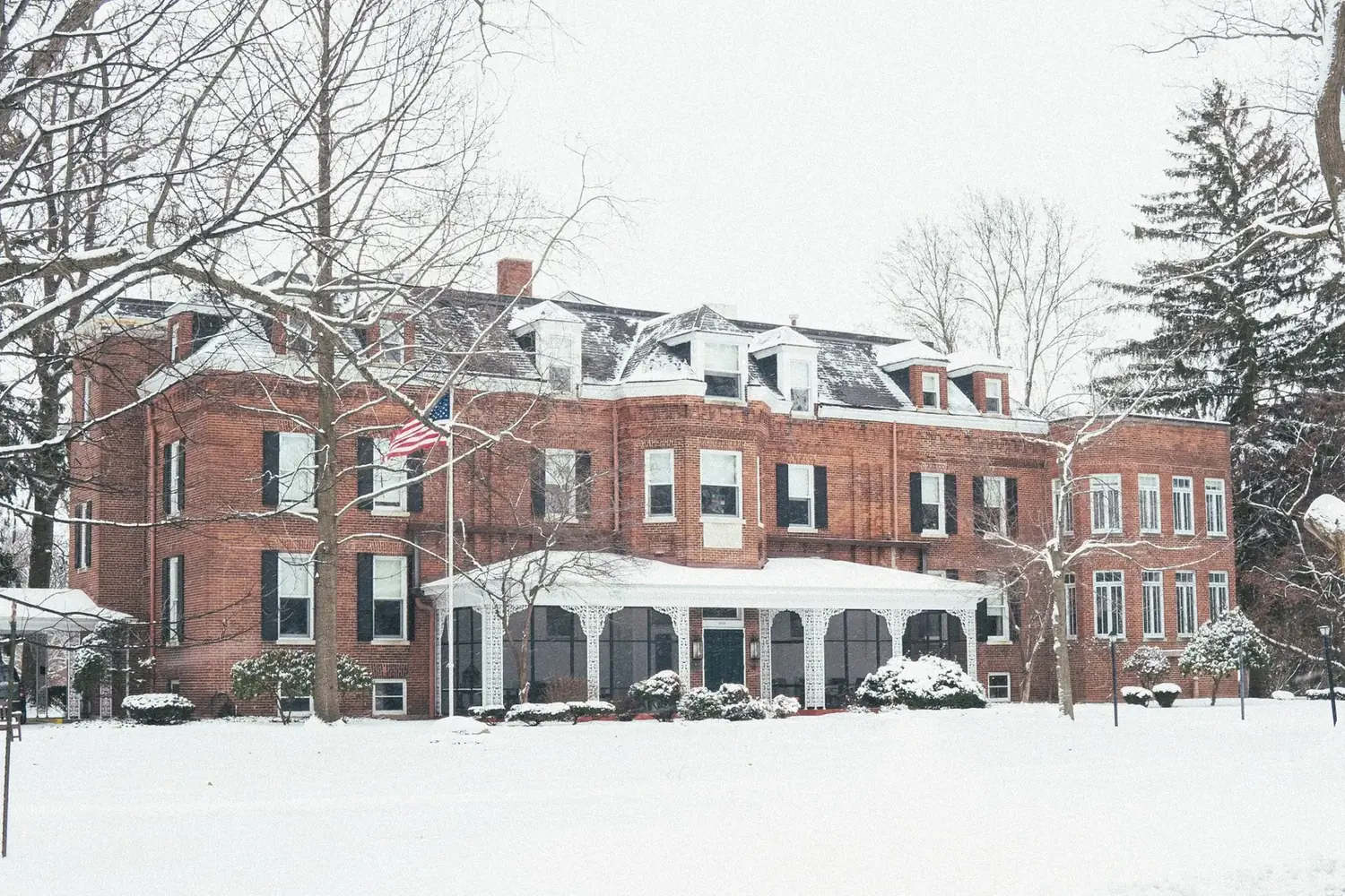 The Old Ruth in winter — full facade with American flag and snow-covered grounds